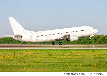 Take-off from the runway of a white passenger aircraft on a clear summer day 121439962