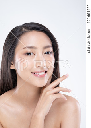 Asian woman young woman with long hair smiles confidently, showcasing her natural beauty and flawless skin in studio setting 121661355