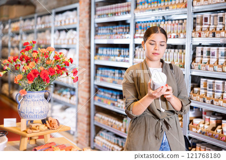 Young woman chooses bottles of paint in shop 121768180