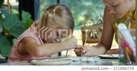 A young mother and her daughter enjoy a creative art session at home  121808729