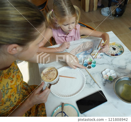 A young mother and her daughter enjoy a creative art session at home  121808942