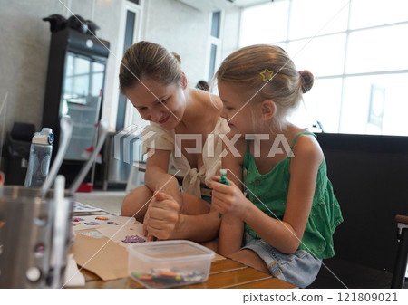 Mother and her daughter paint Halloween cookies  121809021