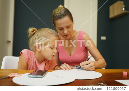 A mother and her young daughter engage in a colorful painting activity  121809037