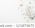 Delicate flower petals scatter around a broken feather pen on a piece of aged parchment. 121873675