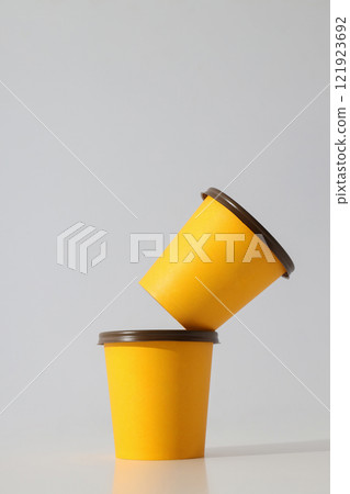 Yellow paper cups with lids on a light background 121923692