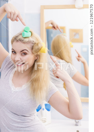 Blonde woman using hair rollers 121967570