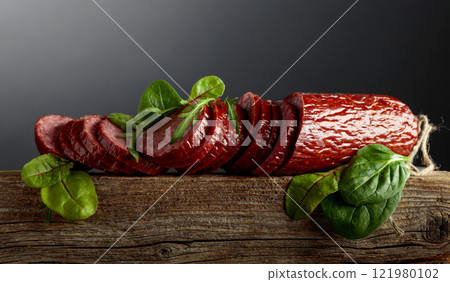 Sliced salami on a old wooden board. 121980102