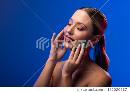 Caucasian woman wearing red lipstick and blue nail polish on blue background, copy space 121020387