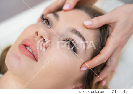 Healer performing set of 32 points of access bars on young woman head, stimulating positive change thoughts and emotions. Alternative medicine concept 121211491