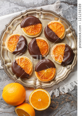 Cookies with caramelized orange and chocolate glaze close-up in a plate. Vertical top view 121238389