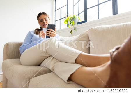 Relaxing on couch, woman shopping online with smartphone and credit card, at home 121316391