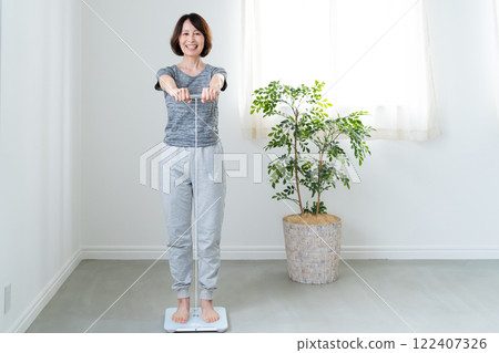 A woman measuring her body weight with a scale 122407326