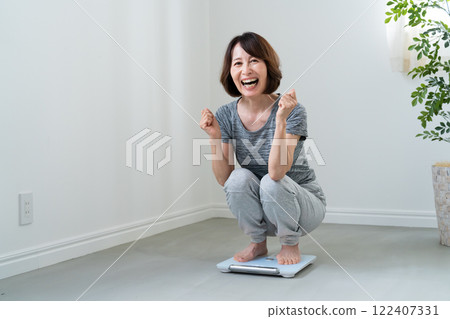 A woman who is happy to weigh herself 122407331