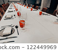 Table set in a restaurant. Glassware, red glasses on a white tablecloth on a table. Eating and drinking utensils. Forks and knives Plates with napkins 122449969