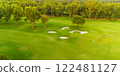 An aerial view of a golf course with sand traps surrounded by vibrant greenery. 122481127