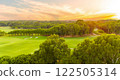 A golden sunset over a golf course surrounded by lush greenery 122505314