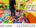 A child exploring a colorful ball pit hand in hand with an adult in a vibrant playground. 122505320