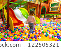 A colorful playground with a child walking toward the slides for a fun ride. 122505321