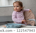 A curious toddler distracted during mealtime, showing independence and playful expression. 122547943