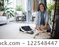 A young woman puts various women's handbags for storage in her home wardrobe. Accessories and bags. 122548447