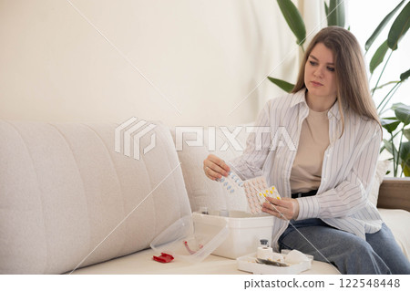 Female housewife checking medicines at domestic first aid kit neatly placing storage organization 122548448