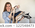 A young woman puts various women's handbags for storage in her home wardrobe. Accessories and bags. 122548473