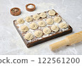 Beef dumplings on a floured wooden board with a rolling pin nearby 122561200