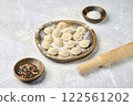 Homemade dumplings prepared on a wooden plate with spices and flour on a kitchen countertop 122561202