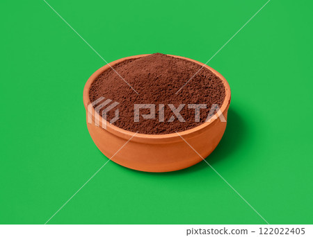 Cacao powder bowl close-up, isolated on a green background. 122022405