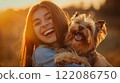 Beautiful girl hugs and cuddles beloved Yorkshire Terrier dog outdoors in sunset. Woman and dog laughing. Human-animal friendship. Happy together.  122086750