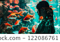 Asian young woman with dark hair female portrait in profile looking at the large aquarium with red fish. Leisure and entertainment. A girl in the zoo. 122086761