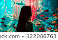 Asian young woman with dark hair female portrait in profile looking at the large aquarium with red fish. Leisure and entertainment. A girl in the zoo. 122086763