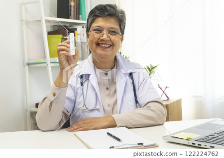 Senior female doctor holding ATK kit in hospital room, covid19 and pandemic concept. 122224762