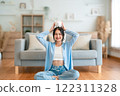 Young Asian woman holding piggy bank and sitting on the floor at home 122311328