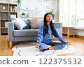 Happy young Asian woman practicing yoga and meditation at home sitting on floor 122375532