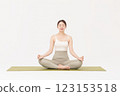 Portrait of a young woman wearing sportswear sitting on a yoga mat and stretching 123153518