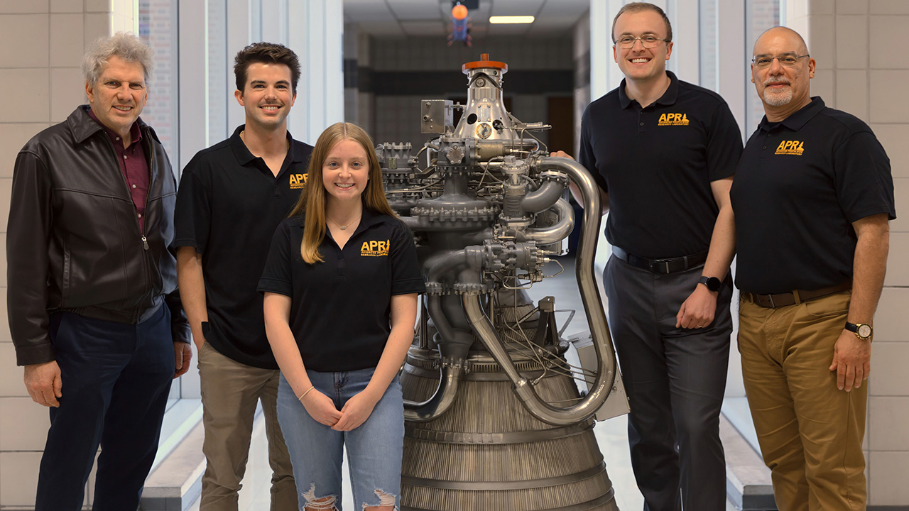 Cutline: Auburn University’s Advanced Propulsion research team stands near a cryogenic RL10 liquid rocket engine. The team is tasked with developing analytical models for cyclonic flows, constructing computational models and studying the stability of different vortex engines. Pictured from left to right are Roy Hartfield, Daniel Little, Emma Signor, Anthony Marcello and Joe Majdalani. 