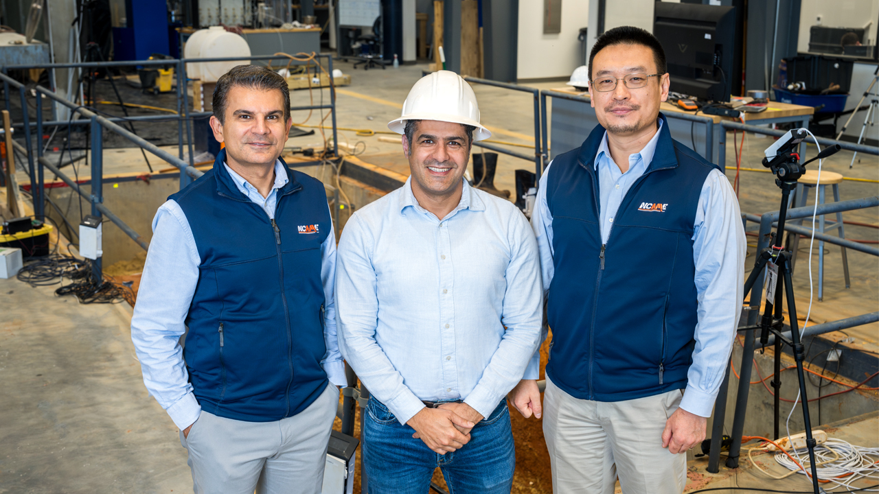 Nima Shamsaei, Philpott-WestPoint Stevens Distinguished Professor of mechanical engineering and director of the National Center for Additive Manufacturing Excellence (NCAME) (left), Ali Khosravi, assistant professor in civil and environmental engineering (middle), and Shuai Shao, associate mechanical engineering professor and NCAME's associate director for research and innovation (right), stand at the Advanced Structural Engineering Laboratory on Auburn University’s campus. The trio are collaborating to develop robot for efficient utility line installation.  