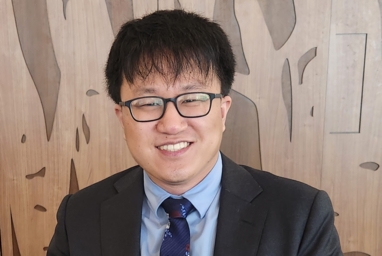 Photo of an East Asian man wearing a dark gray suit and a floral tie