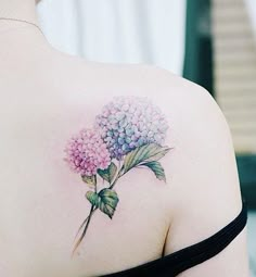 the back of a woman's shoulder with a flower tattoo on her left shoulder