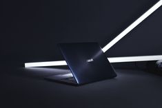 a laptop computer sitting on top of a black table next to a white light strip