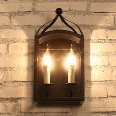 two candles are lit in an old fashioned wall light