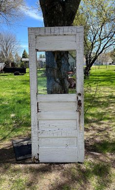 an old outhouse door with a mirror on it in the middle of a field