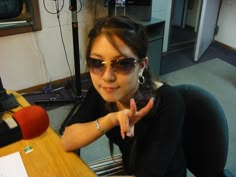 a woman wearing sunglasses sitting at a desk