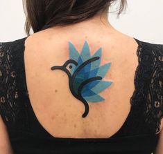 the back of a woman's neck with a blue bird tattoo on her left shoulder