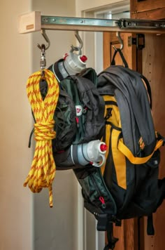 a backpack hanging from a hook in a room with other items attached to the hooks