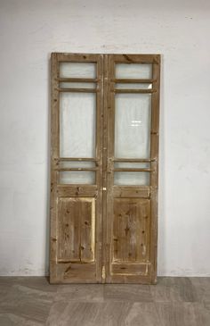 an old wooden door with glass panels on the front and back doors are standing against a white wall