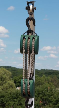 two green and white ropes on top of a pole with trees in the back ground