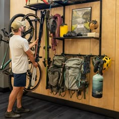 a man is looking at his bike in the shop while holding it up against the wall