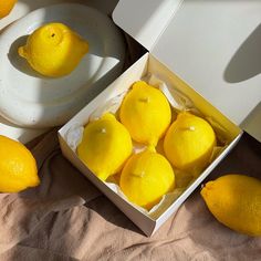 a box filled with lemons sitting on top of a bed next to two plates